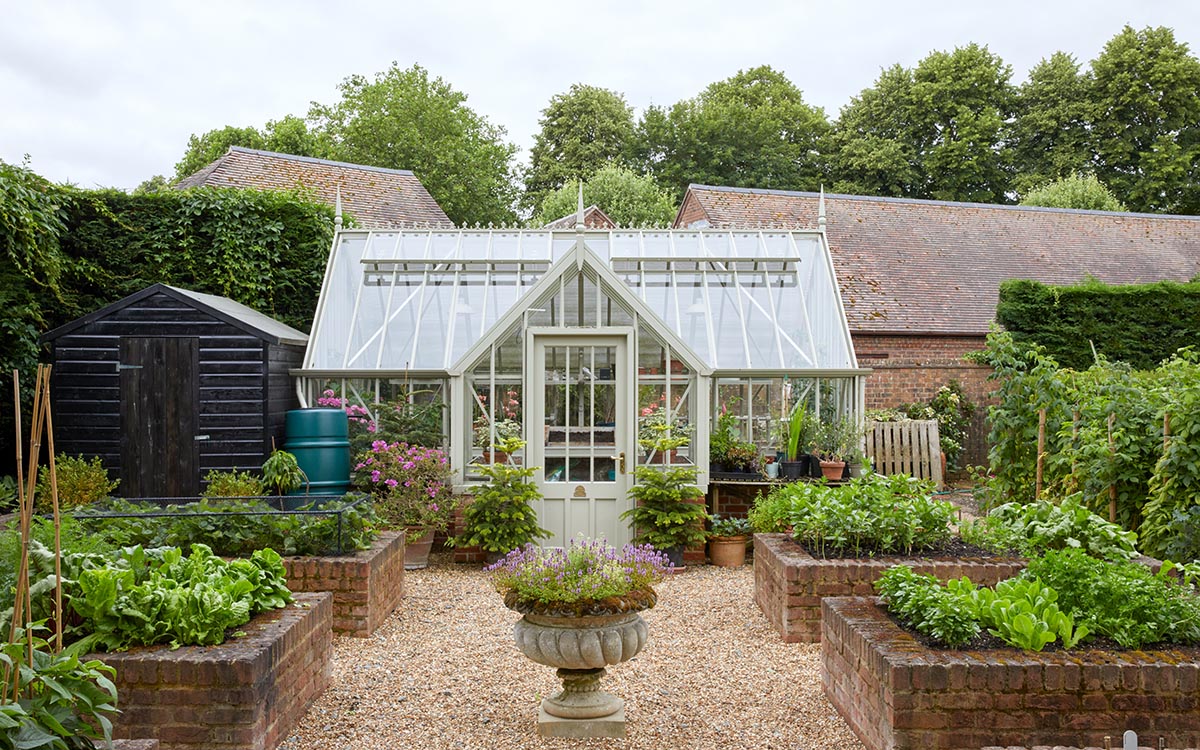 Vegetable garden with raised beds and gravel paths, shed, Alitex greenhouse and water butt.